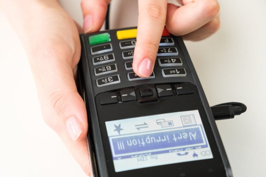 Osoba korzysta z terminala płatniczego, wciskając przyciski na klawiaturze.