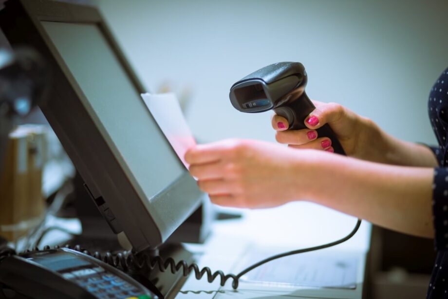 Osoba używa skanera kodów kreskowych przy kasie.