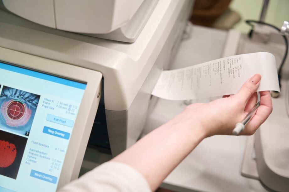 Na zdjęciu widać rękę trzymającą wydruk z drukarki niefiskalnej obok monitora.