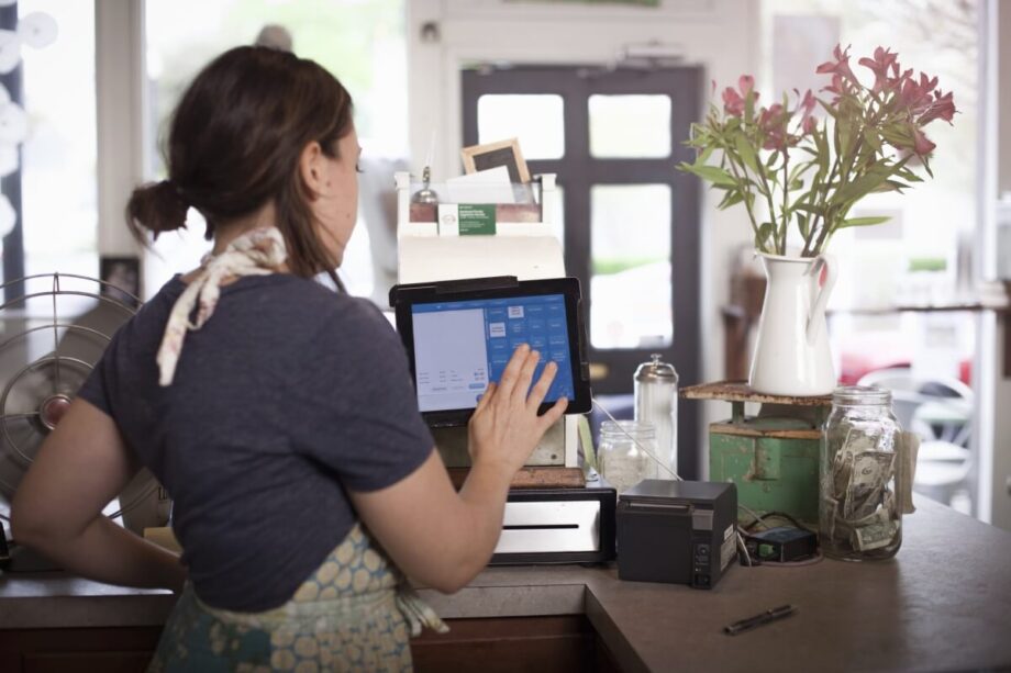 Pracownica obsługuje kasy fiskalne w kawiarni.