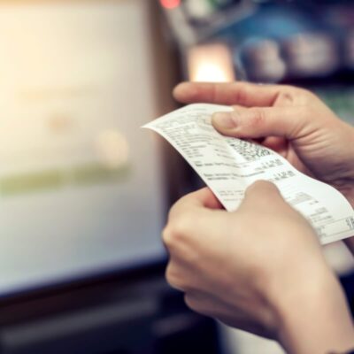 Osoba trzyma wydruk z paragonem, który generują drukarki fiskalne.