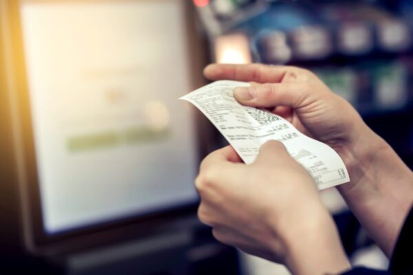 Osoba trzyma wydruk z paragonem, który generują drukarki fiskalne.