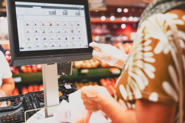 Klient korzysta z oprogramowania sprzedażowego na ekranie dotykowym w sklepie.