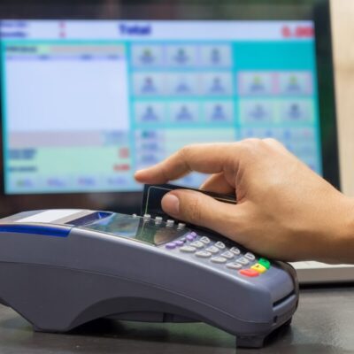 Ręka korzystająca z terminala płatniczego wspieranego przez oprogramowanie sprzedażowe.