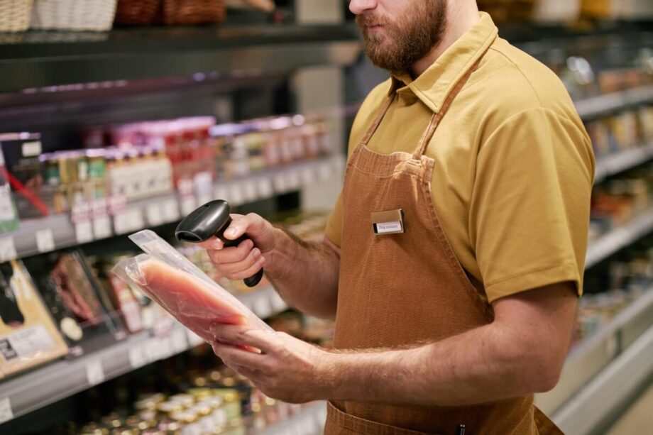 Pracownik sklepu używa skanery kodów kreskowych do zeskanowania produktu.